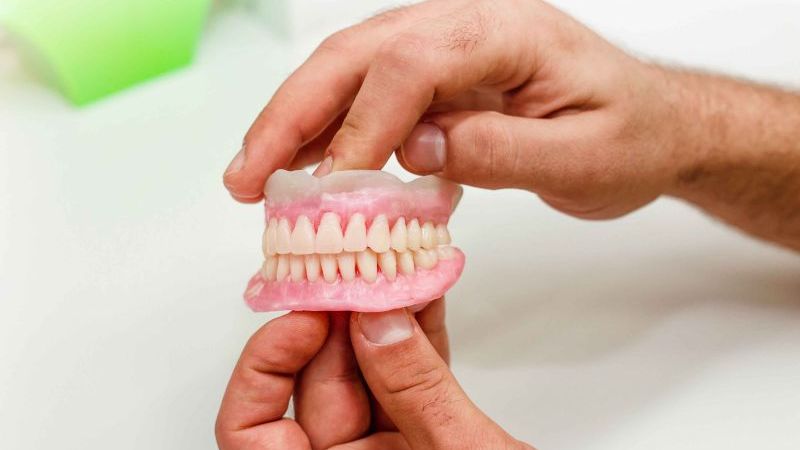 zubná náhrada ktorú v rukách drží pacient