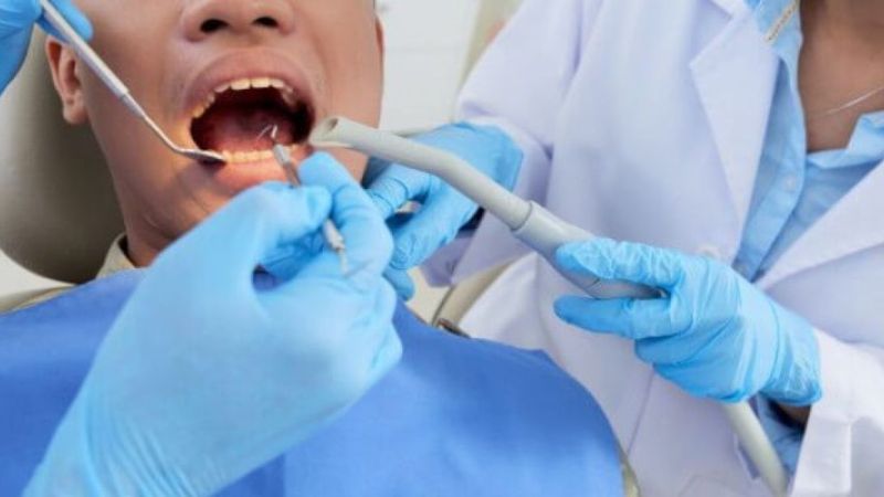 muž sedí v zubárskom kresle a ošetrujú mu mŕtvy zub